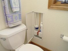 a white toilet sitting next to a bathroom sink under a mirror with two toothbrushes in it