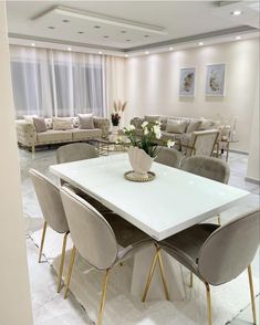 a white table with four chairs around it in a room filled with couches and tables