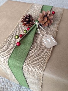 a present wrapped in burlap with a pine cone on top