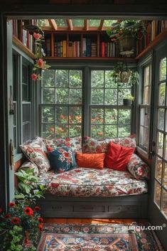 a couch sitting in front of a window filled with lots of plants and bookshelves