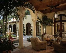 a living room filled with lots of furniture next to a tall palm tree in front of a house