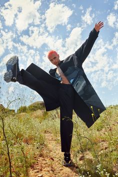 a man with an orange hair is doing a trick in the air while standing on one leg