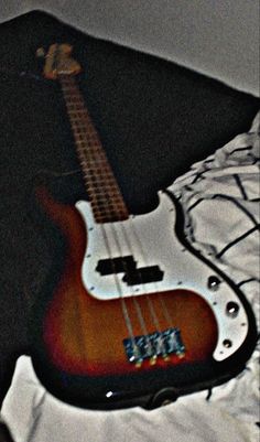 an electric bass guitar laying on top of a bed