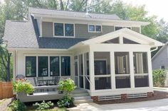 a white house with lots of windows on the front and side of it's porch