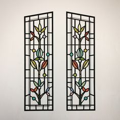 two stained glass windows with leaves and berries on them in a white walled wall area