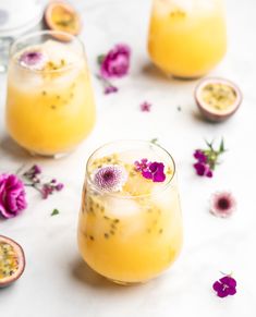 two glasses filled with lemonade and topped with purple flowers on a white tablecloth