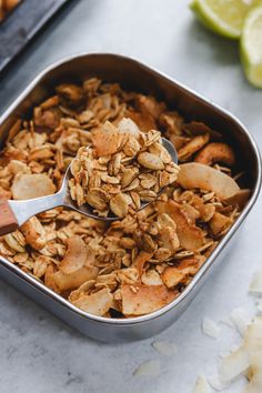 a spoonful of granola in a pan with sliced lemons on the side