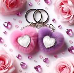 two heart shaped keychais with pink and purple fur on them next to roses