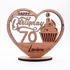 a heart shaped wooden sign with the words happy birthday 70 years on it and a cupcake