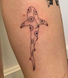 a woman's thigh with a tattoo of a shark and skulls on the side