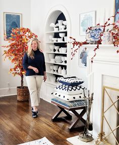 a woman standing in front of a cake on top of a wooden table next to a fireplace