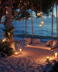 candles are lit in front of a hammock swing on the beach at night