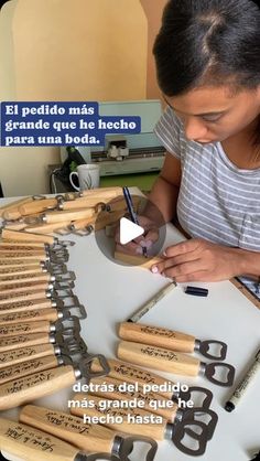 a woman sitting at a table with lots of baseball bats and writing on them in spanish