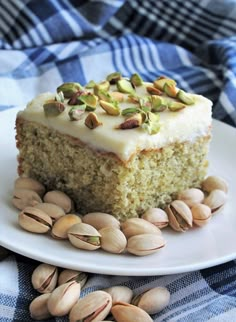 a piece of cake on a plate with pistachios and nuts around it