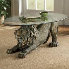 a glass table with a lion statue sitting on top of it next to a potted plant