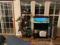 a fish tank sitting on top of a wooden floor next to a bed and window