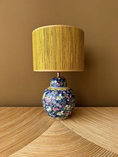 a blue and white vase sitting on top of a wooden table next to a lamp