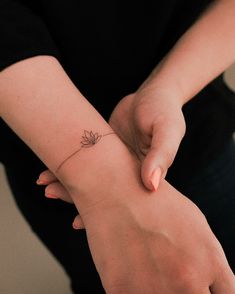 a woman's arm with a small flower tattoo on the left side of her wrist