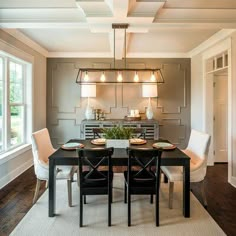 a dining room table with four chairs and a chandelier hanging from the ceiling