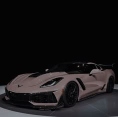 a pink sports car is on display at an auto show in front of a black background