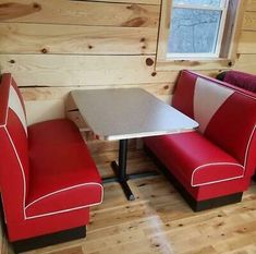 two red chairs and a white table in a room with wood paneling on the walls