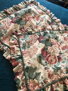 the blanket is laying on top of the bed with ruffles and floral print