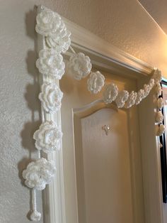 a white door handle with crocheted flowers hanging from it's side on the wall