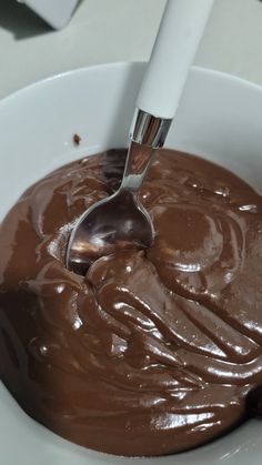 a spoon in a white bowl filled with chocolate