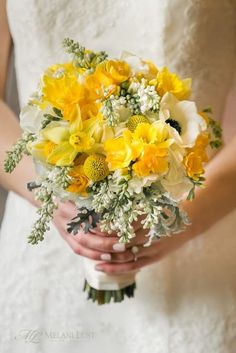 a bride holding a bouquet of yellow and white flowers