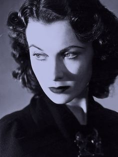 an old black and white photo of a woman with her eyes closed, looking at the camera