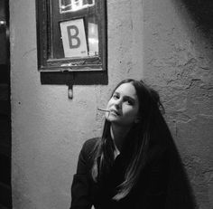 a woman sitting on the floor in front of a wall with a sign above her head