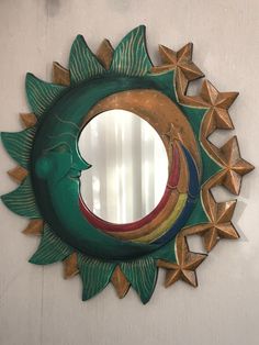 a mirror that is on the wall with stars around it and a sun face in the middle