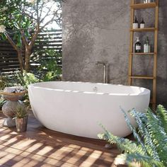 a white bathtub sitting on top of a wooden floor next to plants and potted plants