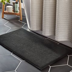 a black mat on the floor next to a bathtub and shower curtain in a bathroom