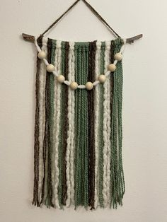 a green and white wall hanging with beads