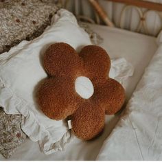 a brown flower shaped pillow sitting on top of a bed next to a white pillow