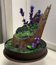 a tree stump with moss and purple flowers