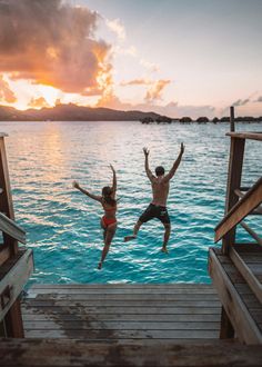 two people jumping into the water from a dock