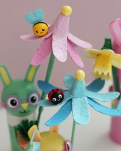 some paper flowers are sitting in vases with bugs on them and ladybugs