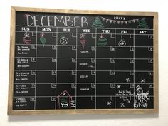 a chalkboard calendar is hanging on the wall in front of a white wall with christmas decorations