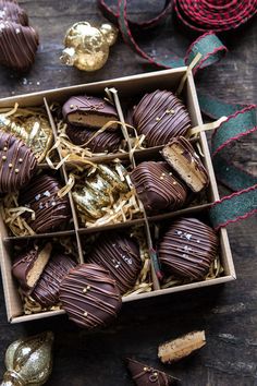 a box filled with chocolate covered cookies on top of a wooden table next to christmas decorations