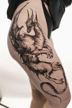 a woman's thigh with a dragon tattoo on her leg and the bottom part of her thighs