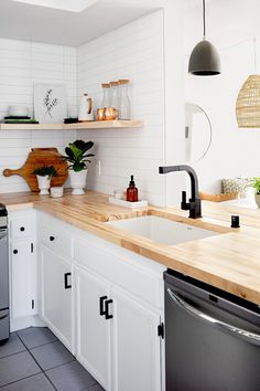 a kitchen with white cabinets and wooden counter tops