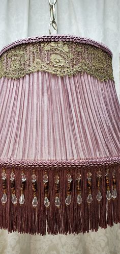 a pink lamp shade with tassels hanging from it