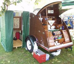 an old fashioned trailer is parked in the grass with its door open and shelves full of items