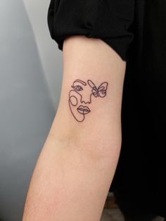 a woman's arm with a face and butterfly tattoo on the left inner arm