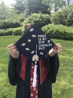 a person in a graduation cap and gown holding up a sign that says today is my new favorite day