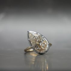 a pear shaped diamond ring sitting on top of a table