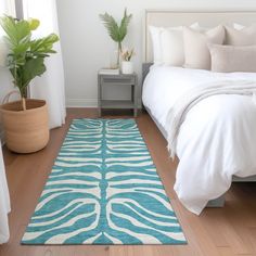 a bedroom with a bed, rug and plant in the corner on the floor next to it