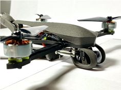 an image of a remote controlled flying device that is on the ground and has wheels attached to it